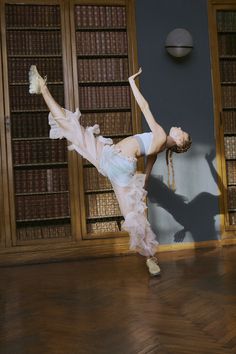 a woman is dancing in front of bookshelves