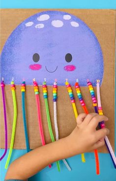 a child is holding colorful toothbrushes in front of a paper bag with an octopus on it