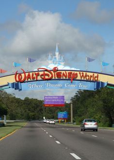 the entrance to disney world with cars driving under it