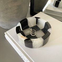 a black and white ring dish sitting on top of a table next to a vase