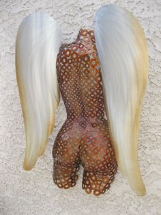 a sculpture of an angel's wings on a white background with brown circles and dots