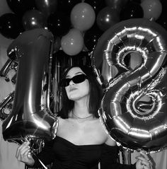 a woman wearing sunglasses and holding balloons in front of her face with the number 8 on it