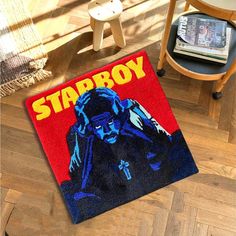 a starboy door mat on the floor next to a chair and table with a book