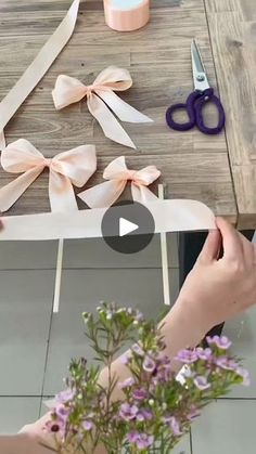 someone cutting ribbon on a table with scissors and flowers in the foreground, while another person is holding a flower