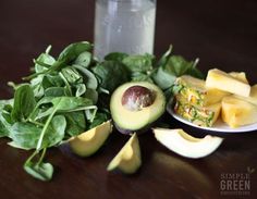 an avocado, spinach and other vegetables on a table