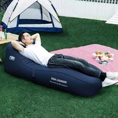 a man is laying on an inflatable lounger while relaxing at a picnic