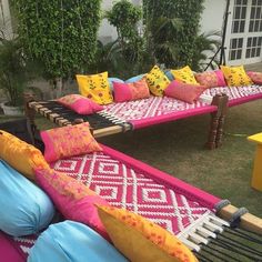 a row of pink and yellow couches with pillows on them in front of a house