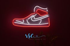 a neon sign that is lit up in the dark with a pair of shoes on it