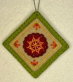 a decorative ornament hanging on a white wall with red and green trimmings