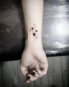 a woman's hand with a small star tattoo on her left wrist and the other arm