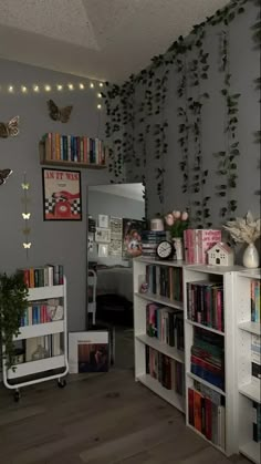 a room filled with lots of books on top of a hard wood floor next to a white book shelf