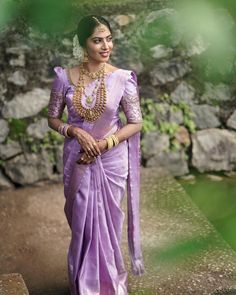 a woman wearing a purple sari and gold jewelry