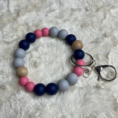 a pink, blue and grey beaded bracelet on a white furnishing with a pair of scissors