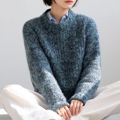 a woman sitting on the floor wearing a sweater