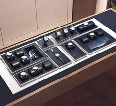 an assortment of watches on display in a wooden case with black and white leather accents