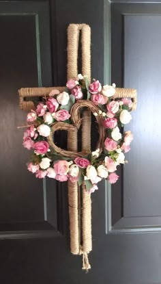 a cross made out of rope and flowers hanging from it's side on a door