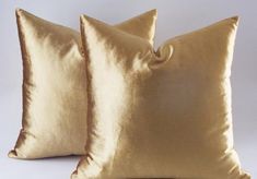 two gold pillows sitting next to each other