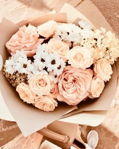 a bouquet of flowers sitting on top of a brown bag next to a pair of shoes