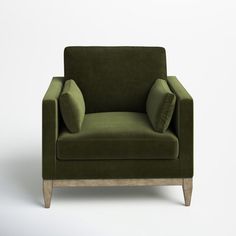 a green chair with two pillows on the armrests and a white wall in the background