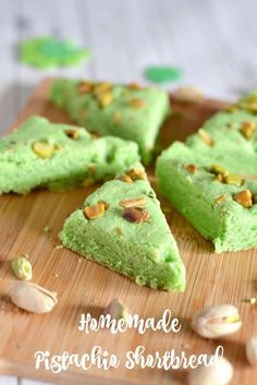 homemade pistachio shortbreads on a wooden cutting board with nuts around them