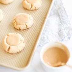 peanut butter cookies on a cookie sheet with a bowl of peanut butter