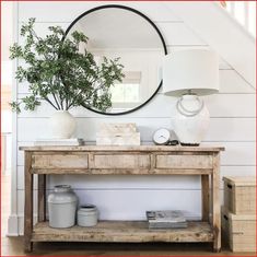 a wooden table sitting under a mirror next to a stair case