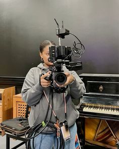 a man holding a video camera in front of a piano and other musical instrument equipment