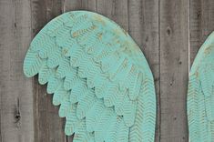 two green angel wings sitting on top of a wooden fence next to eachother