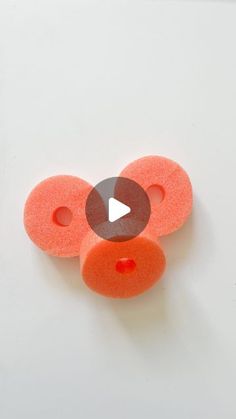 an orange object with two holes in the middle and one hole at the top that has a video play button on it