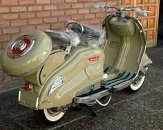 a green scooter parked next to a brick wall