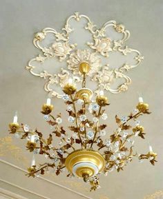 a chandelier hanging from the ceiling in a room with gold and white decor