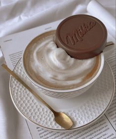 a cappuccino on a saucer with a spoon sits atop a menu