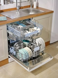 an open dishwasher in a kitchen next to a sink