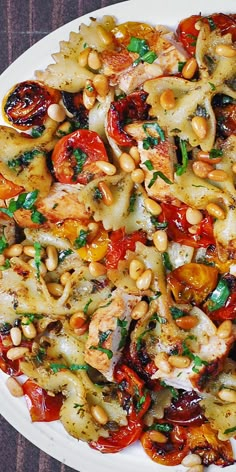 a white plate topped with pasta and veggies on top of a wooden table