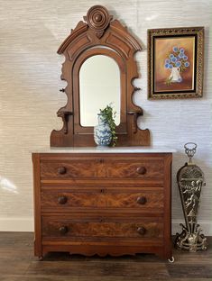 an antique dresser with mirror and vase on top