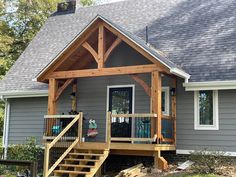 a house with a porch and stairs leading up to the front door that is open