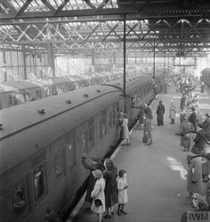 an old black and white photo of people standing next to trains at a train station