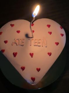 a white heart shaped cake with red hearts on it and the words ate teen written in frosting