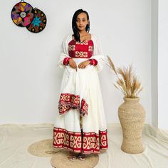 This stunning red Habesha dress features a stylish crop top and matching skirt, designed to bring bold elegance to any occasion. The intricate patterns on the fabric add a touch of traditional craftsmanship while the modern crop and skirt style offer a chic and contemporary look. Perfect for standing out at cultural events, parties, or casual outings, this unique Habesha dress effortlessly combines tradition with a modern twist. Key Features: Cultural Heritage: Adorned with exquisite handwoven details that honor Ethiopia's rich traditions. Flattering Design: The flowing silhouette ensures you look stunning at weddings, festivals, or any event where you want to shine. Ethical Craftsmanship: Handmade by skilled Ethiopian artisans, embracing tradition while making a bold fashion statement. Ca Red Bohemian Set With Traditional Drape, Bohemian Style Red Set With Traditional Drape, Bohemian Style Red Traditional Drape Sets, Bohemian Red Set With Traditional Drape, Traditional Red Floor-length Dress, Red Dresses With Traditional Patterns For Ceremonies, Red Dress For Navratri Traditional Ceremonies, Traditional Red Maxi Length Dresses, Red Dress With Pallu And Traditional Drape