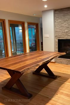 a large wooden table sitting on top of a hard wood floor next to a fire place