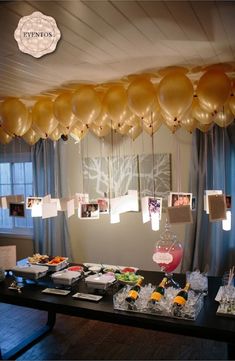 balloons and pictures hang from the ceiling above a table filled with food, drinks and snacks