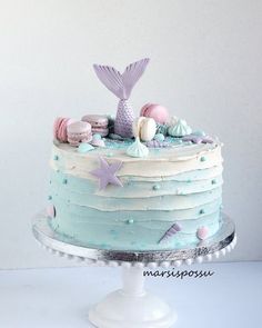 the cake is decorated with pastel blue icing and pink seashells on top