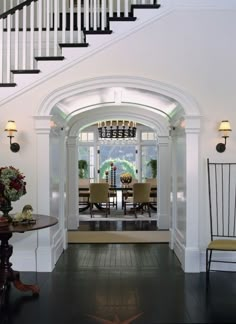 an entry way with stairs leading up to a dining room table and chairs in the center