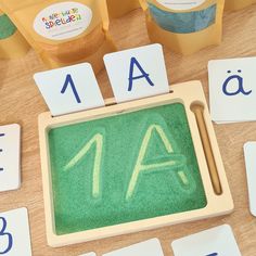 a wooden table topped with lots of different types of letters and numbers next to cupcakes