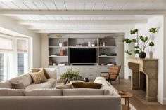 a living room filled with furniture and a flat screen tv mounted on a wall above a fireplace