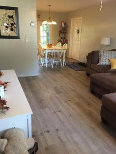 a living room filled with furniture next to a dining room table and chairs on top of a hard wood floor