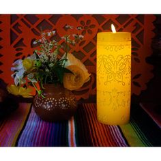 a yellow candle sitting next to a vase with flowers