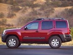 a red jeep is parked on the side of the road in front of some hills