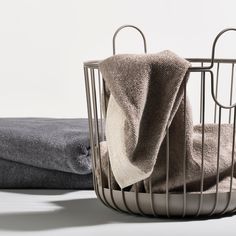 two towels in a metal basket next to each other on a white surface with one folded up