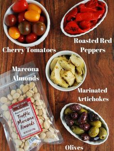 different types of olives, tomatoes, and peppers in small white bowls on a wooden table